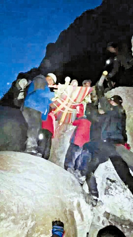 救援隊(duì)員用自制的簡(jiǎn)易擔(dān)架抬傷者。