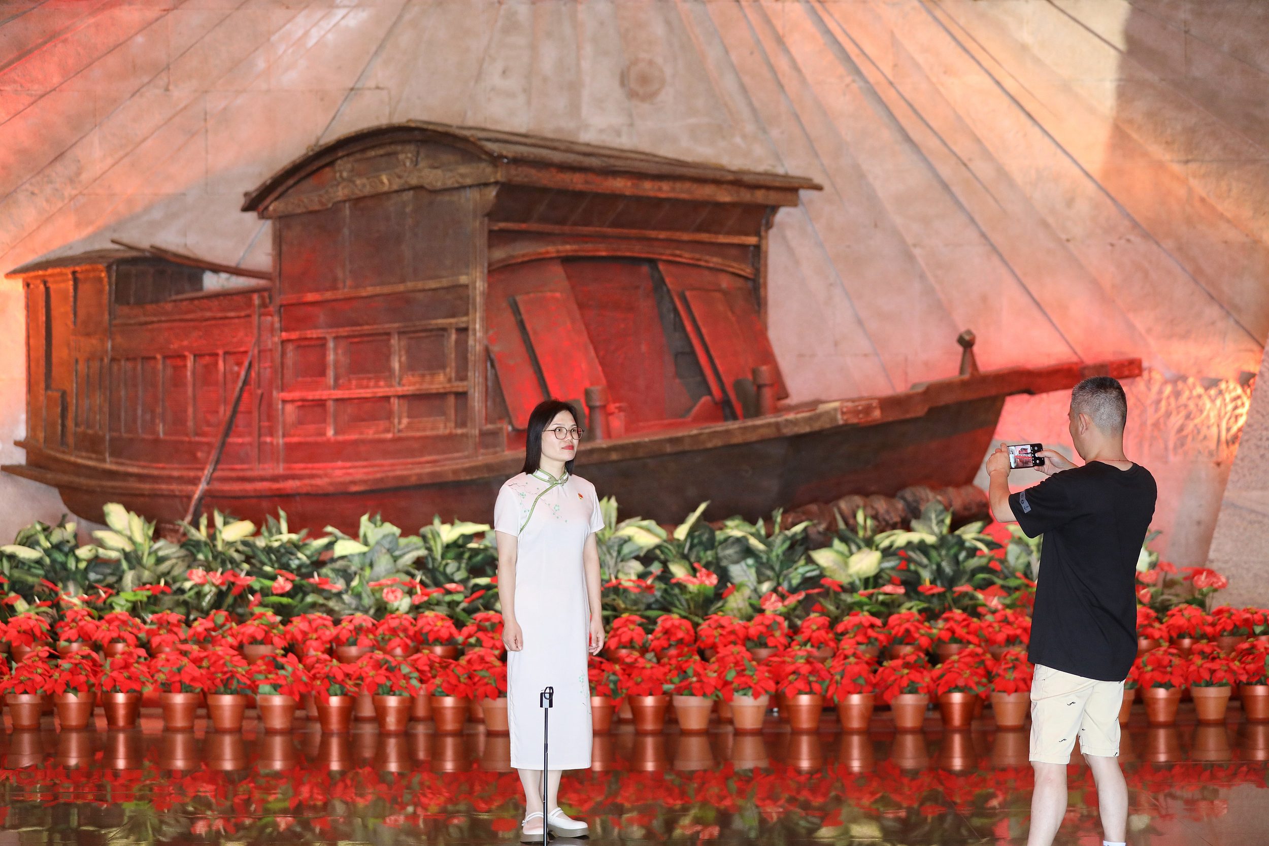 2025年6月24日，浙江嘉興，游客在南湖革命紀(jì)念館與紅船雕塑合影。（圖片來源：視覺中國）