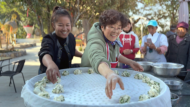 【2】旅居者趙發(fā)英（圖左二）教曼海村村民做花卷。陶思源-攝